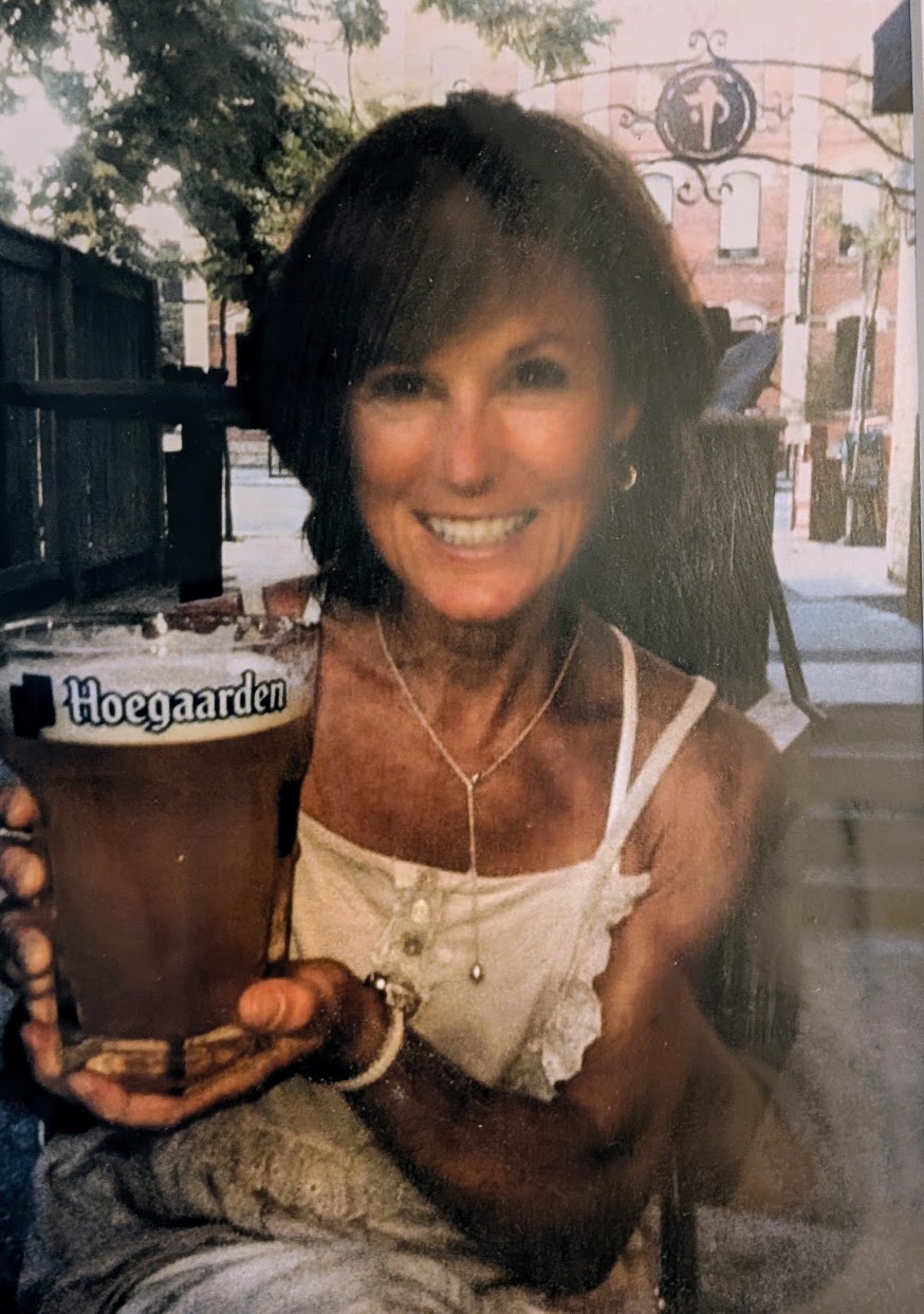 Sue on a patio, holding up a pint of Hoegaarden